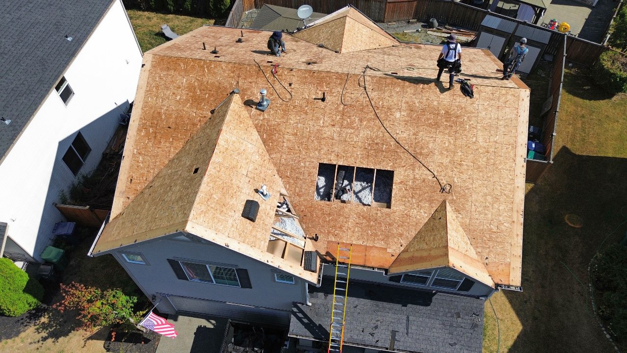 Roofing crew on bare decking during a two-story roof replacement